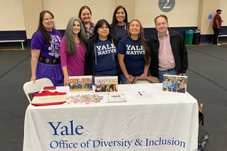 Group of people standing behind a table that has Yale Office of Diversity and Inclusion branding.