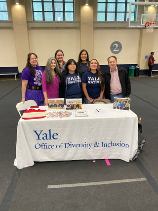 Group of people standing behind a table that has Yale Office of Diversity and Inclusion branding.